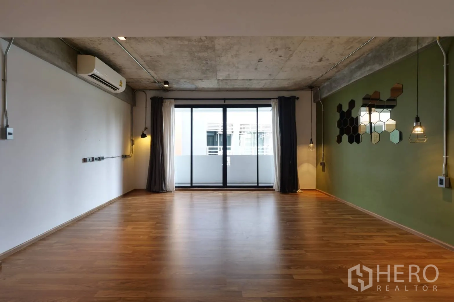 Townhouse for rent in Khlong Toei, Bangkok - Empty multipurpose room with sliding doors to balcony and pendant lights.