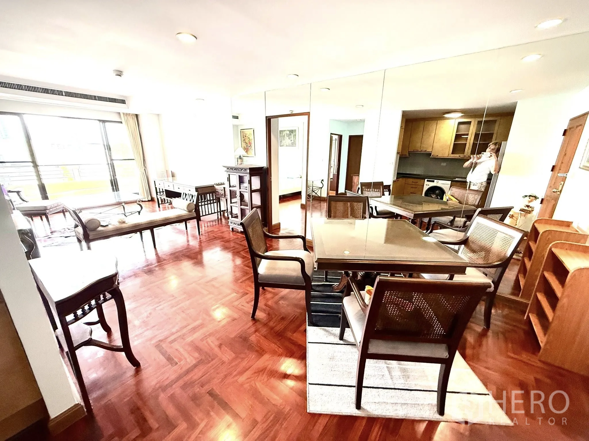 Condominium for rent in Sathon, Bangkok - Open‑plan dining and living zone with parquet flooring and mirror wall.
