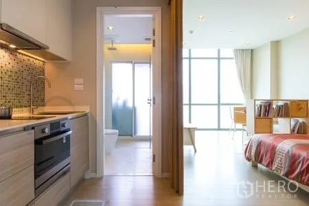 คอนโด ให้เช่าในWatthana, Bangkok - ผังห้องแบบโอเพ่นคอนเซ็ปต์ เห็นครัวย่อม ประตูห้องน้ำ และห้องนอนสว่างพร้อมหน้าต่างบานใหญ่