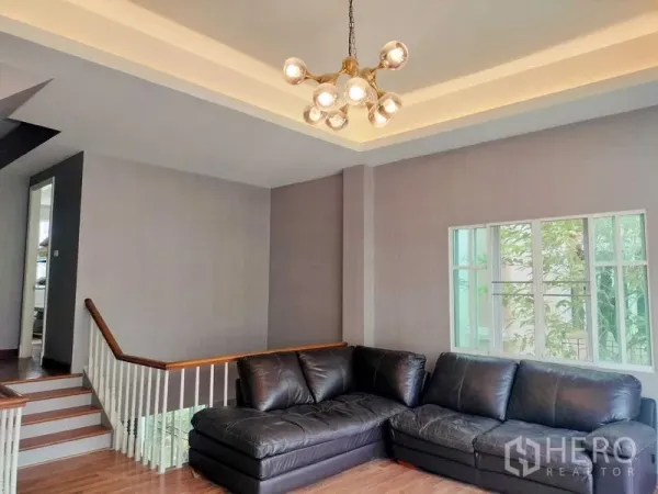 ทาวน์เฮาส์ ให้เช่าในBueng Kum, Bangkok - ห้องนั่งเล่นแบบสเต็ปพร้อมโซฟาหนังตัว L ฝ้าเพดานหลุมและโคมระย้า