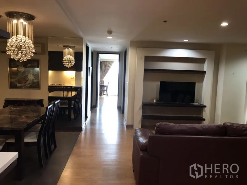 公寓 出租在Watthana, Bangkok - 开放式客餐厅，木地板与水晶吊灯，走廊尽头设有内置电视墙。