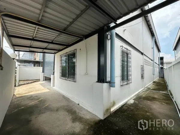 工厂 出租在Bang Bua Thong, Nonthaburi - 厂房侧边带顶棚的通道，窗户装有防盗栏，便于装卸与服务通行。