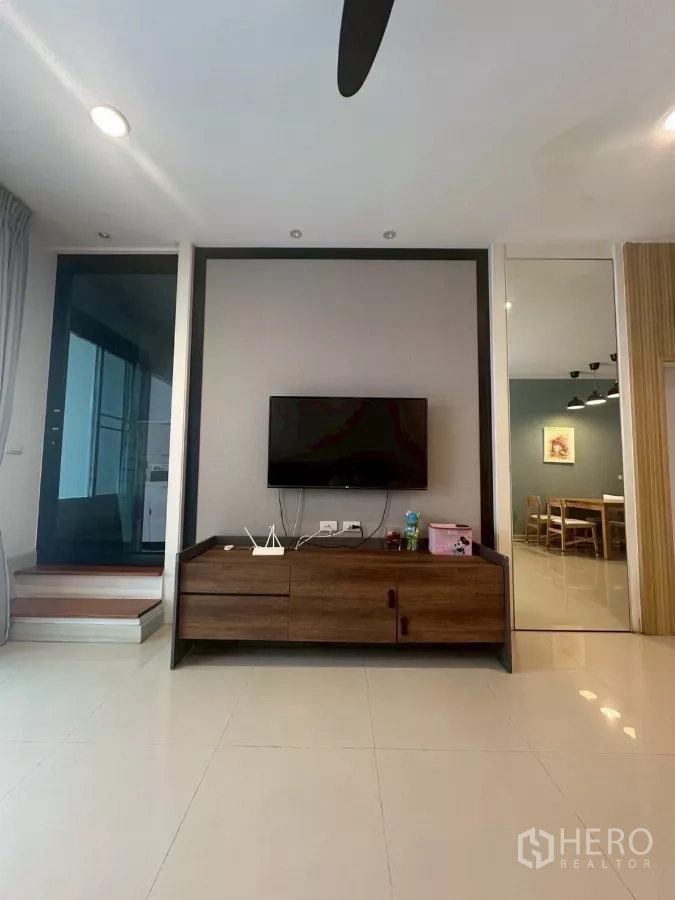Townhouse for rent in Chom Thong, Bangkok - Living room TV wall with wooden media console and ceiling fan.