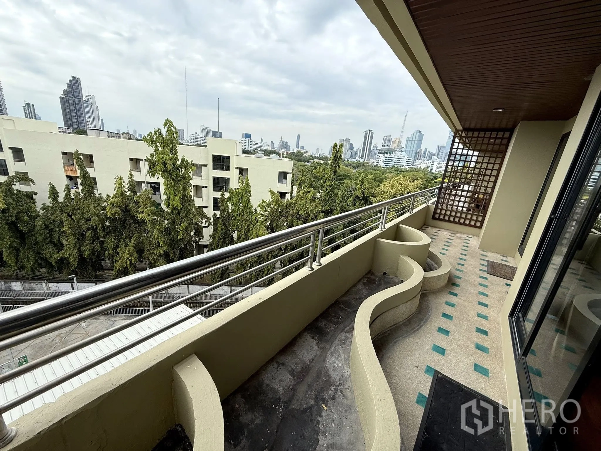 Condominium for rent in Sathon, Bangkok - Long covered balcony with curved planters and city skyline views over Yen Akat.