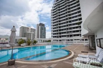 Condominium for sale in Watthana, Bangkok - Outdoor swimming pool with sun loungers and city high-rise views.