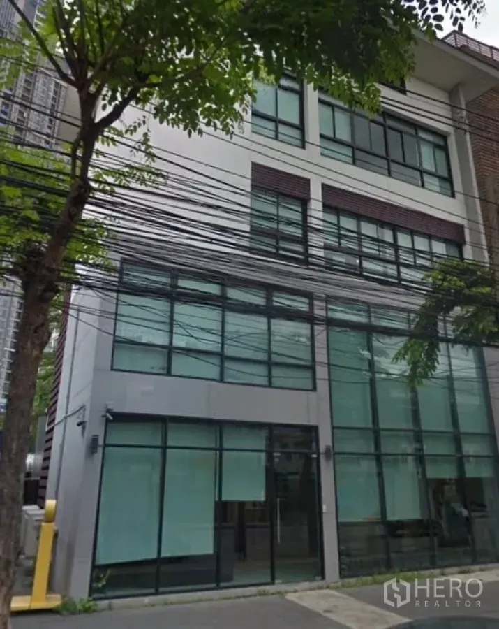 带办公室的家 出租在Phra Khanong, Bangkok - 多层现代家用办公楼，大片落地窗与街道行道树。