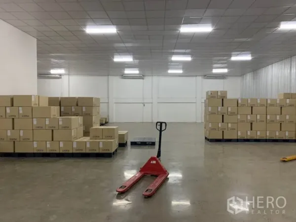 คลังสินค้า ให้เช่าในYan Nawa, Bangkok - ภายในโกดังสว่าง ไฟ LED พื้นคอนกรีตขัดมัน กล่องสินค้าบนพาเลท และแฮนด์พาเลทสีแดง