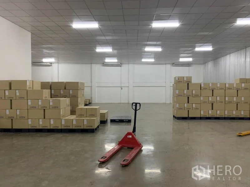 คลังสินค้า ให้เช่าในYan Nawa, Bangkok - ภายในโกดังสว่าง ไฟ LED พื้นคอนกรีตขัดมัน กล่องสินค้าบนพาเลท และแฮนด์พาเลทสีแดง