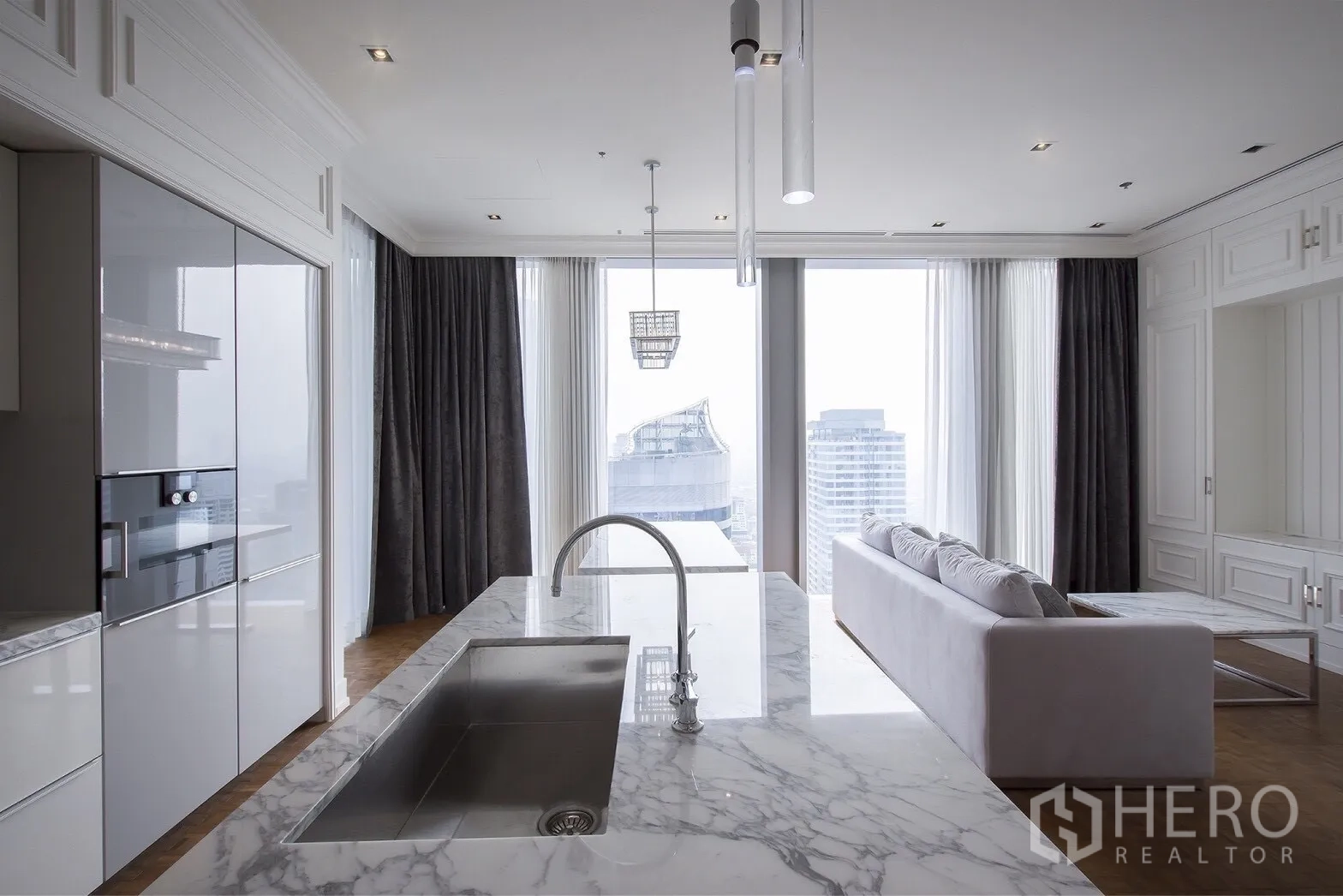 คอนโด ให้เช่าในBang Rak, Bangkok - ไอส์แลนด์หินอ่อนพร้อมอ่างล้างจาน มองออกไปยังโซนนั่งเล่นและวิวเมืองผ่านหน้าต่างสูง