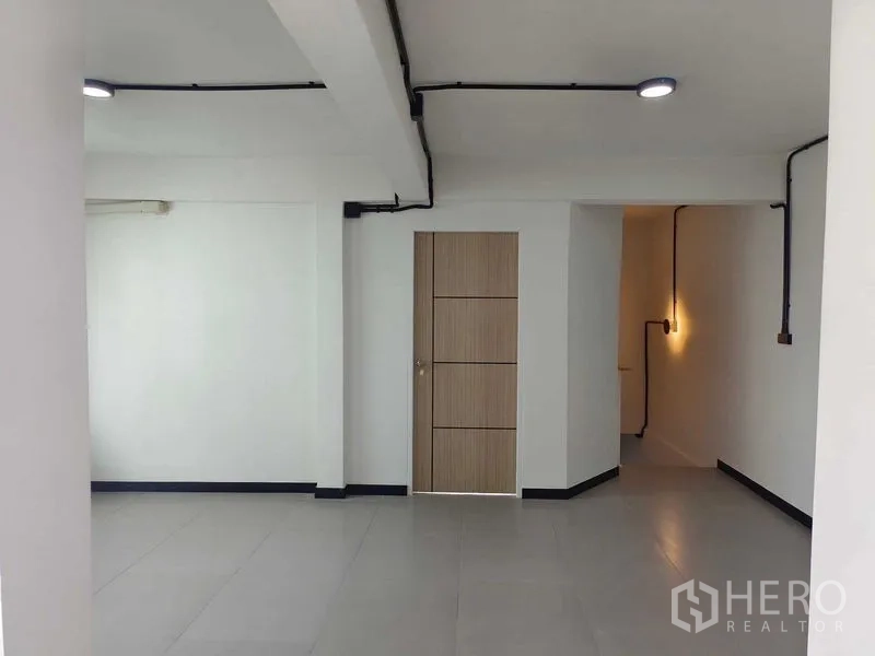 Townhouse for sale in Bang Phlat, Bangkok - Minimal room with modern wood door and recessed corridor lighting.