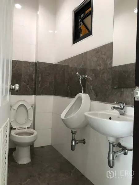 工厂 出租或出售在Bang Phli, Samut Prakan - 办公室内干净的瓷砖卫生间，含洗手盆、小便斗与镜子。