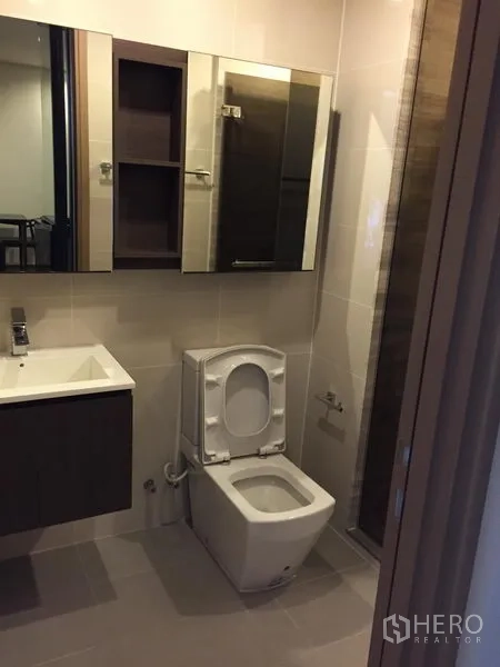 Condominium for rent in Watthana, Bangkok - Contemporary bathroom with wall‑mounted vanity, mirrored cabinets and a glass shower area.