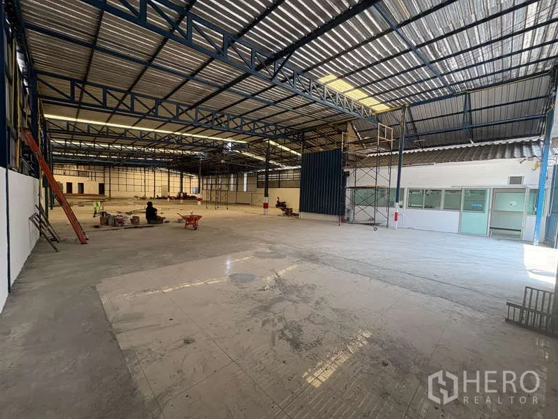 货栈 出租在Prawet, Bangkok - 开放式仓库地面，层高充裕，钢柱与脚手架，一侧设有办公室，便于车辆装卸。