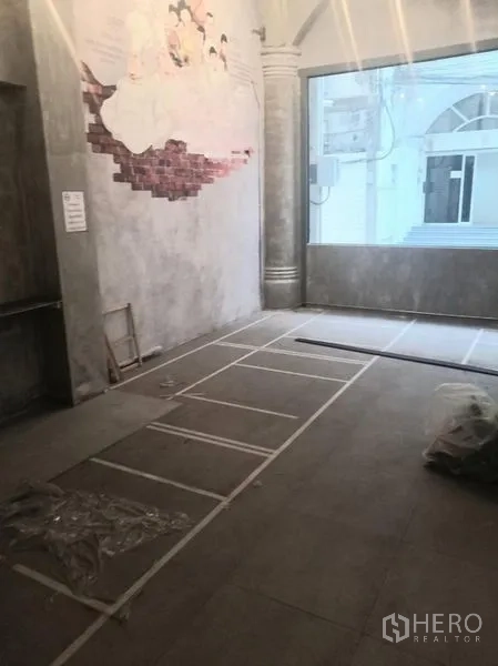 零售空间 出租在Watthana, Bangkok - 角落区域，墙面壁画与大尺寸展示窗和拱形立柱。