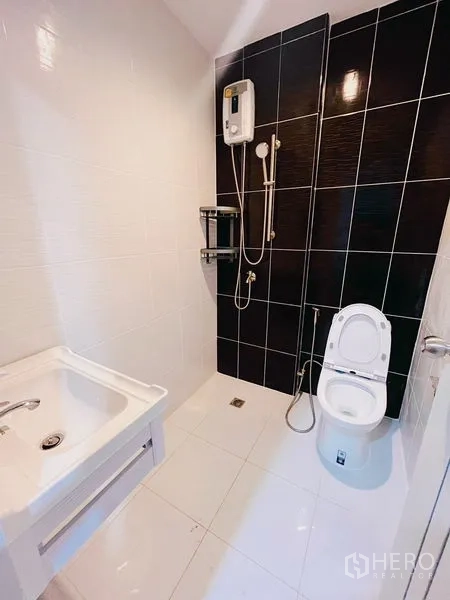 联排别墅 出租在Huai Khwang, Bangkok - 现代卫生间，黑色强调墙、淋浴套装与热水器。