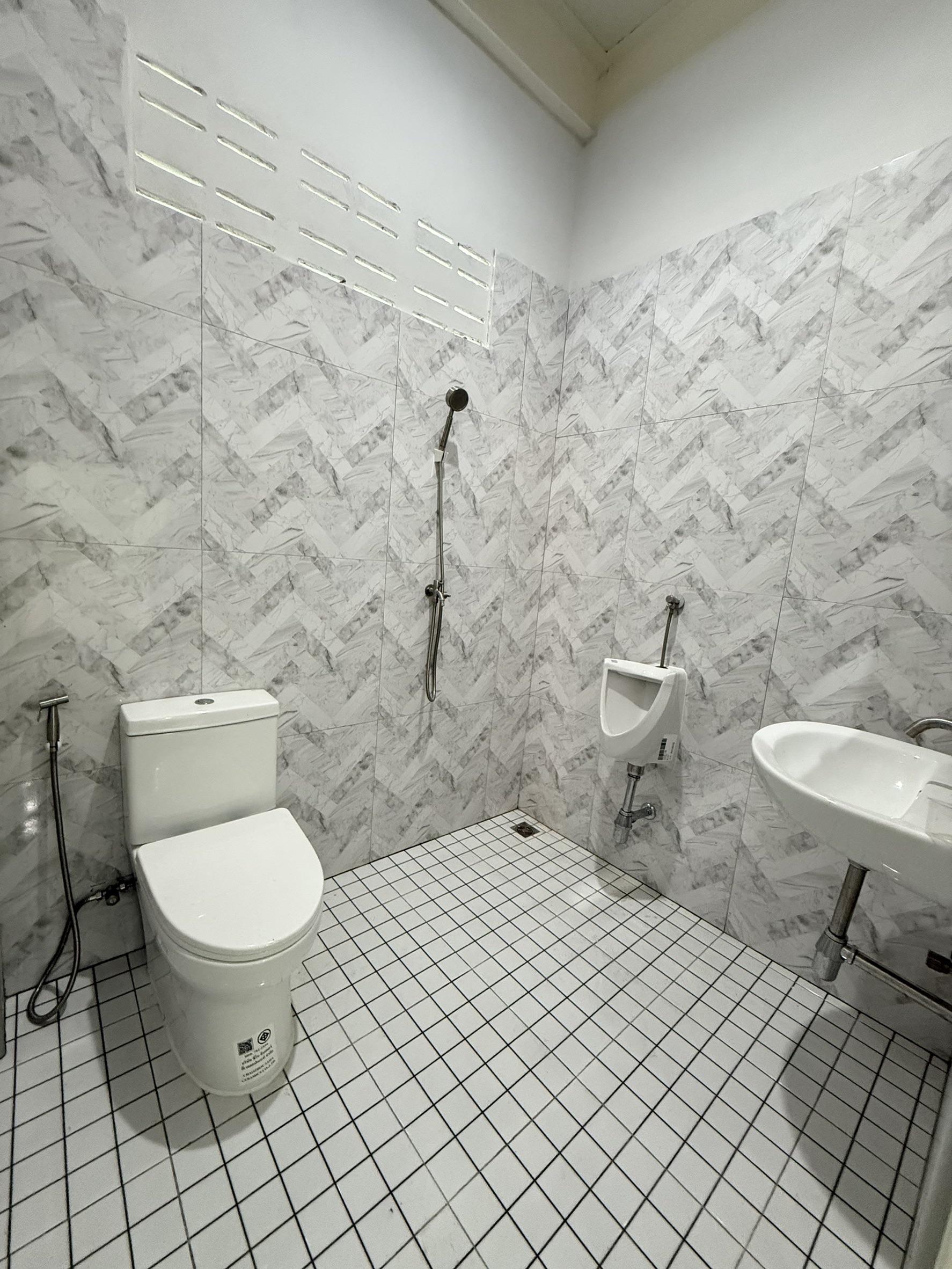 Warehouse for rent in Lat Krabang, Bangkok - Clean tiled restroom with toilet, urinal, sink and handheld shower.