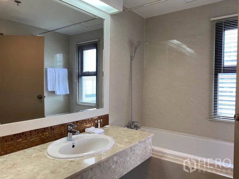 公寓 出租在Watthana, Bangkok - 浴室配浴缸、宽台面洗手盆与带百叶的窗户。