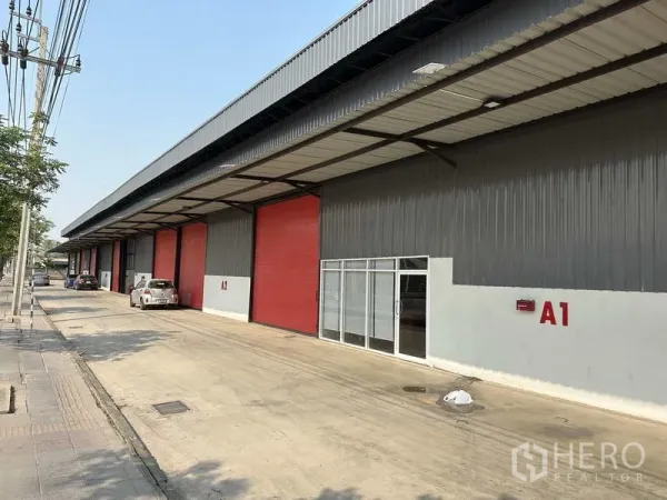 คลังสินค้า ให้เช่าในKhlong Sam Wa, Bangkok - แถวโกดังสมัยใหม่ในคลองสามวาพร้อมประตูม้วนสีแดง ทางเข้าออฟฟิศกระจก และลานขนถ่ายมีหลังคา