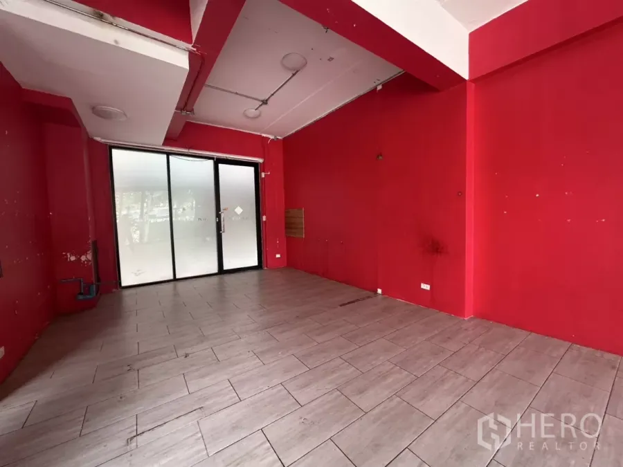 零售空间 出租在Khlong Toei, Bangkok - 一层商铺空间，红色墙面、灰色地砖，配磨砂玻璃推拉门入口。