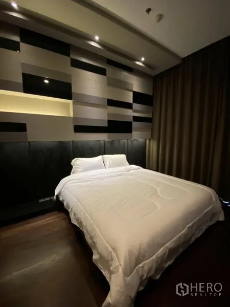 公寓 出租在Watthana, Bangkok - 次卧设几何艺术背景墙与嵌灯，深色窗帘围合大床。