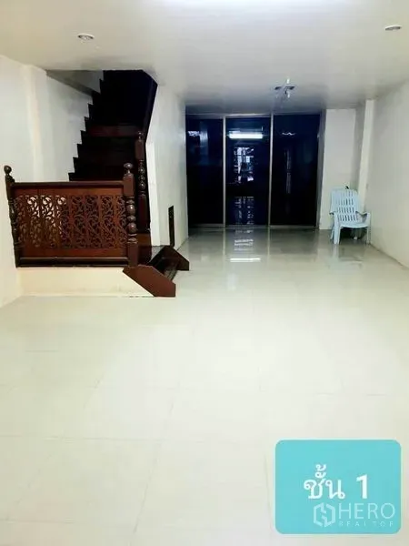 联排别墅 出售在Khlong Toei, Bangkok - 一层宽敞客厅，白色地砖与雕花木楼梯