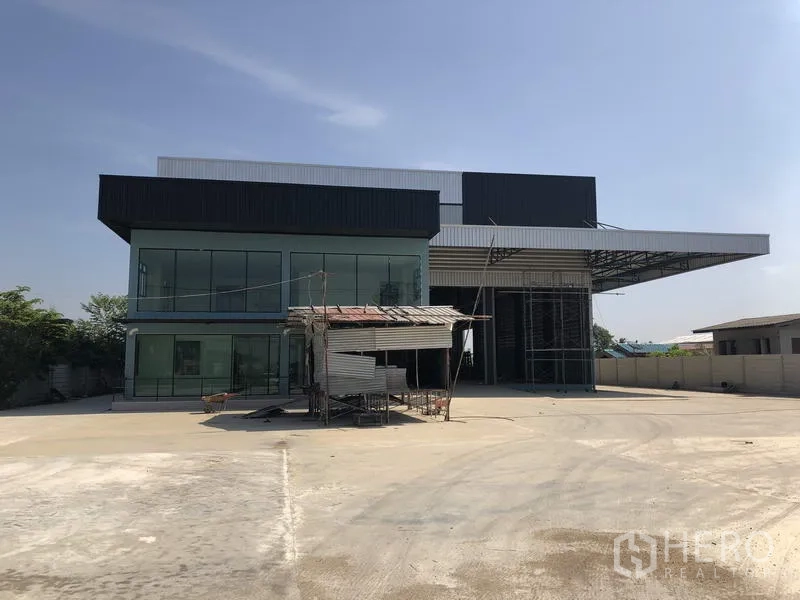 Factory for rent in Lam Luk Ka, Pathum Thani - Modern factory exterior in Lam Luk Ka, Pathum Thani with glass-fronted offices and a wide concrete yard.