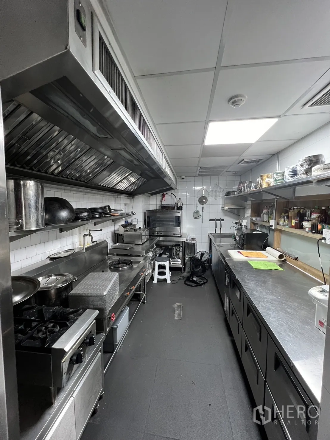 พื้นที่ขายปลีก ให้เช่า - ครัวสแตนเลสเชิงพาณิชย์ มีฮูดดูดควันและเคาน์เตอร์เตรียมอาหารยาว