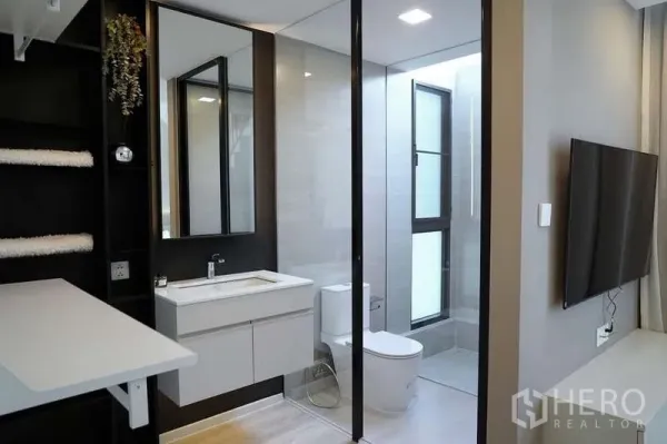 Detached House for rent in Saphan Sung, Bangkok - Contemporary bathroom with glass shower, vanity and toilet separated by slim black-frame partitions.