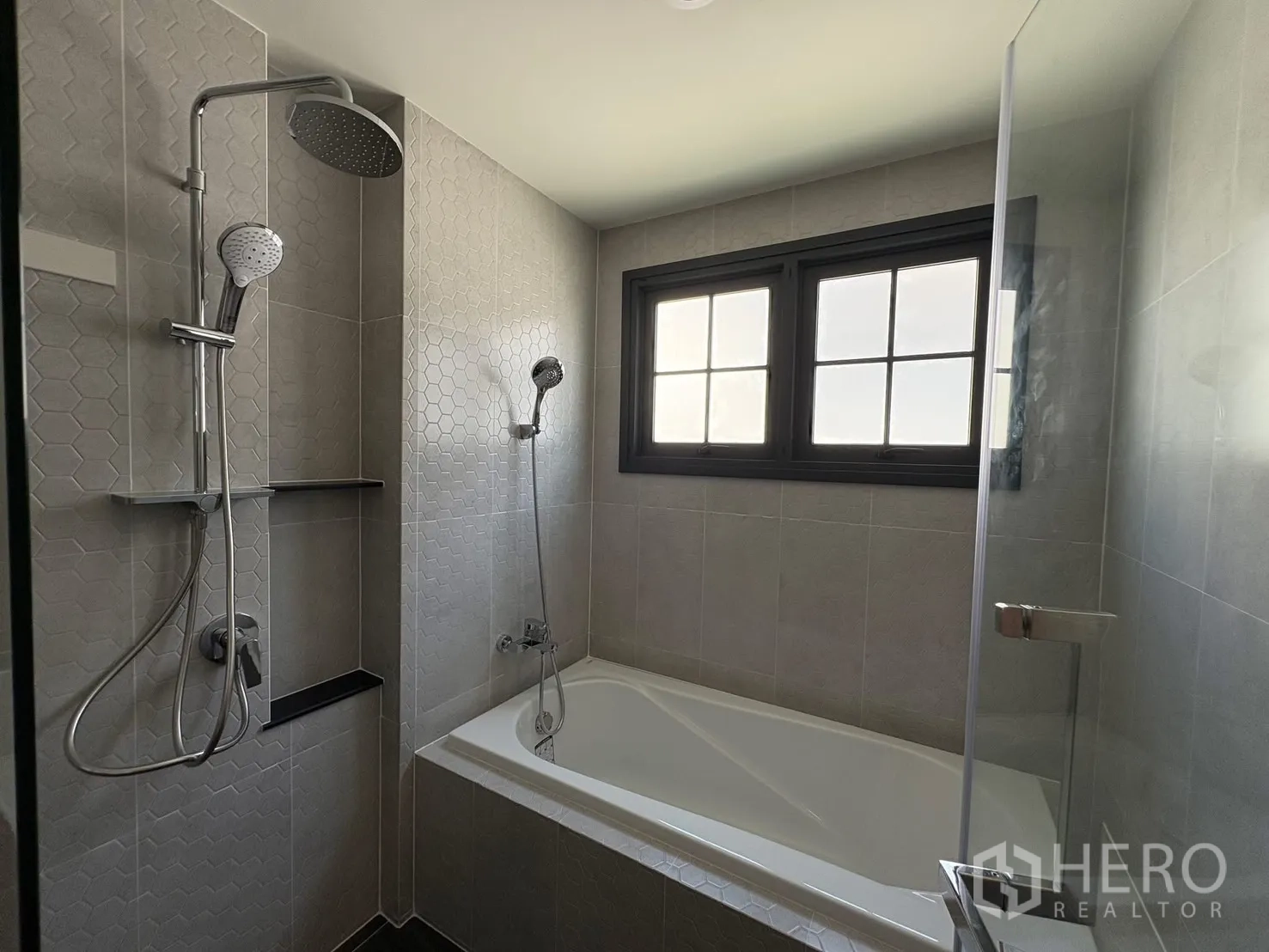 Detached House for rent in Bang Phli, Samut Prakan - Bathroom with bathtub, glass shower screen, rain shower and hexagon accent tiles.