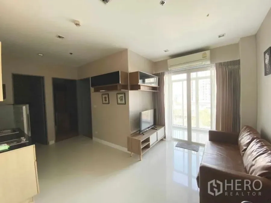 Condominium for rent in Phra Khanong, Bangkok - Bright open-plan living and kitchen with balcony access and air conditioning.