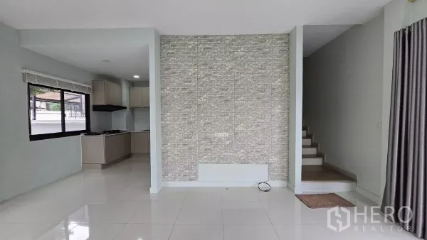 Townhouse for rent or sale in Saphan Sung, Bangkok - Bright open-plan living area with accent tile wall, stairs and glossy floors.