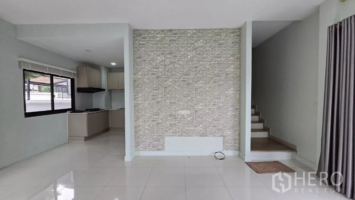 Townhouse for rent or sale in Saphan Sung, Bangkok - Bright open-plan living area with accent tile wall, stairs and glossy floors.