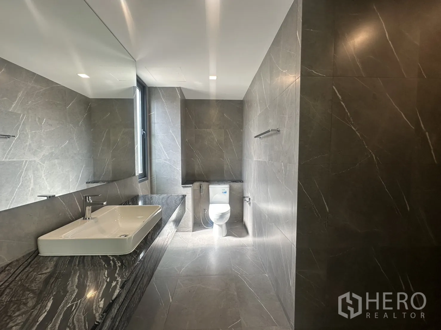 Home Office for rent or sale in Suan Luang, Bangkok - Contemporary bathroom with long stone counter, sink, and window.