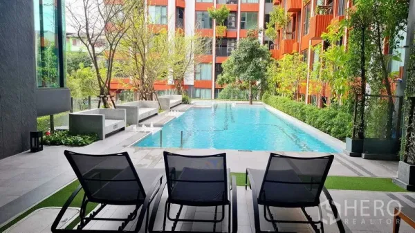 Condominium for rent in Phra Khanong, Bangkok - Modern condominium swimming pool with sun loungers and lush landscaping.