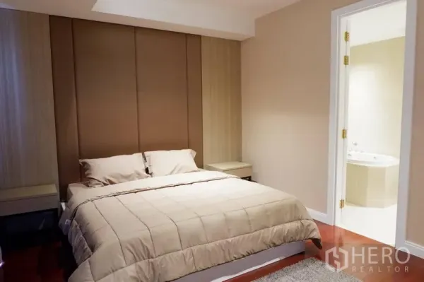 Condominium for rent in Pathum Wan, Bangkok - Master bedroom with upholstered headboard and en-suite bathroom featuring a bathtub.
