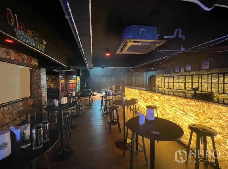 零售空间 出租在Watthana, Bangkok - 夜间酒吧视角，背光吧台、吧凳和小舞台角落
