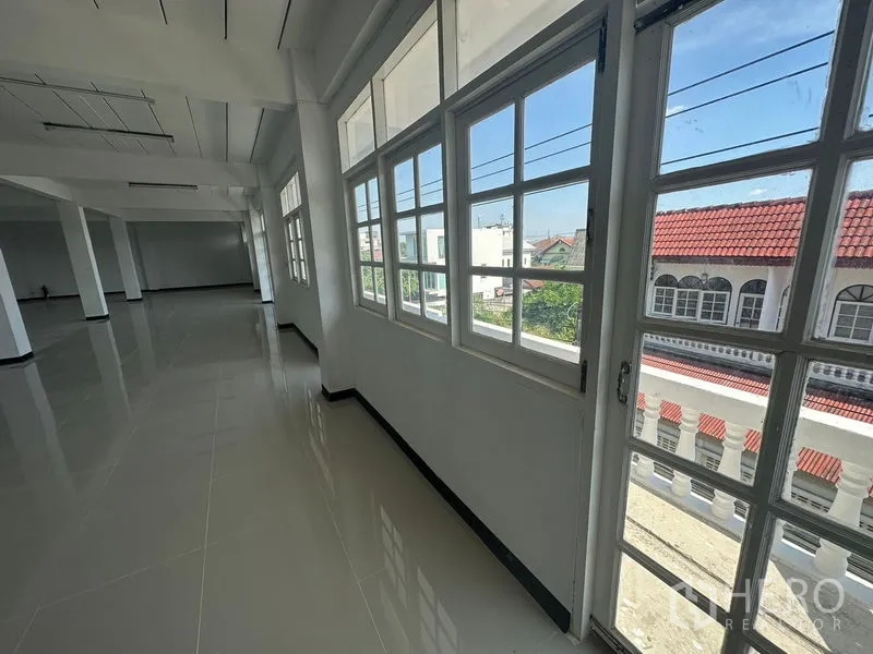 Home Office for rent in Phra Khanong, Bangkok - Window-lined walkway with a door to the balcony and local neighborhood view.