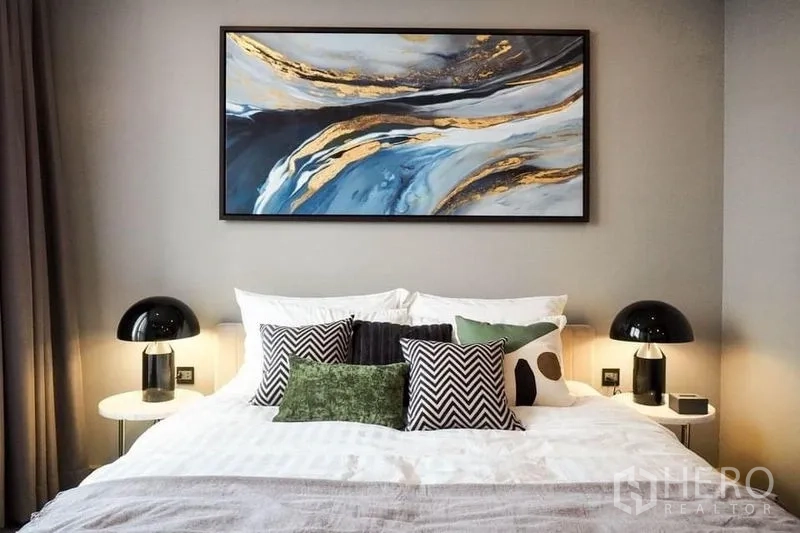 公寓 出租或出售在Huai Khwang, Bangkok - 明亮卧室，双人床、抱枕、床头灯与抽象画