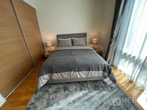 Condominium for rent in Watthana, Bangkok - Cozy bedroom with grey bedding, wooden sliding wardrobe and sheer curtains.