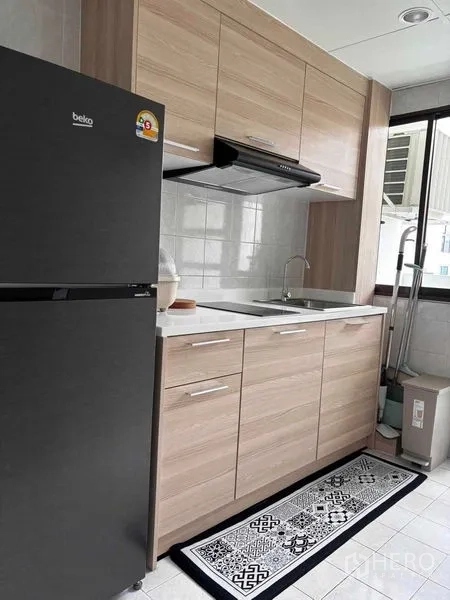 Condominium for rent in Watthana, Bangkok - Separate kitchen with wood cabinets, sink, range hood and a large refrigerator.