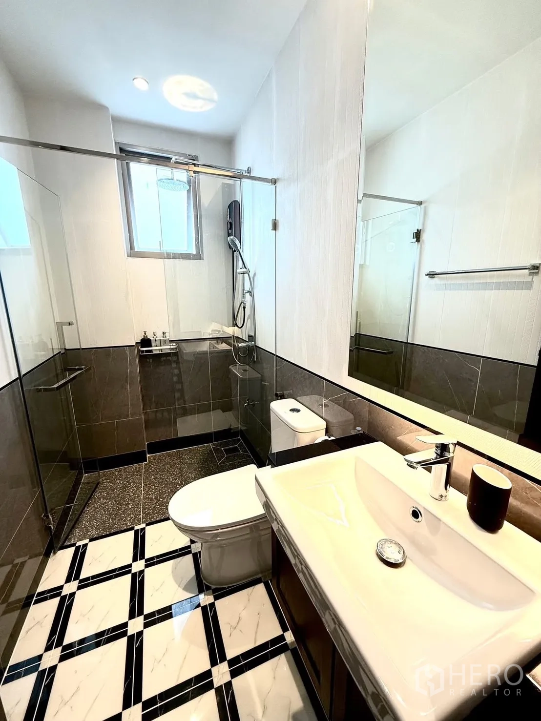 Detached House for rent or sale in Bang Phli, Samut Prakan - Bathroom with glass shower enclosure, rain shower, toilet and long vanity under a window.