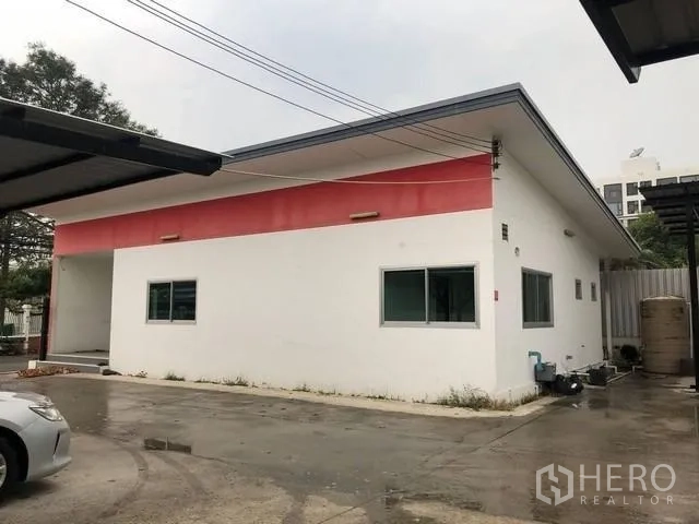 ที่ดิน ให้เช่าในPhra Khanong, Bangkok - อาคารชั้นเดียวสีขาวคาดแดง ข้างลานคอนกรีตและโรงจอดรถ