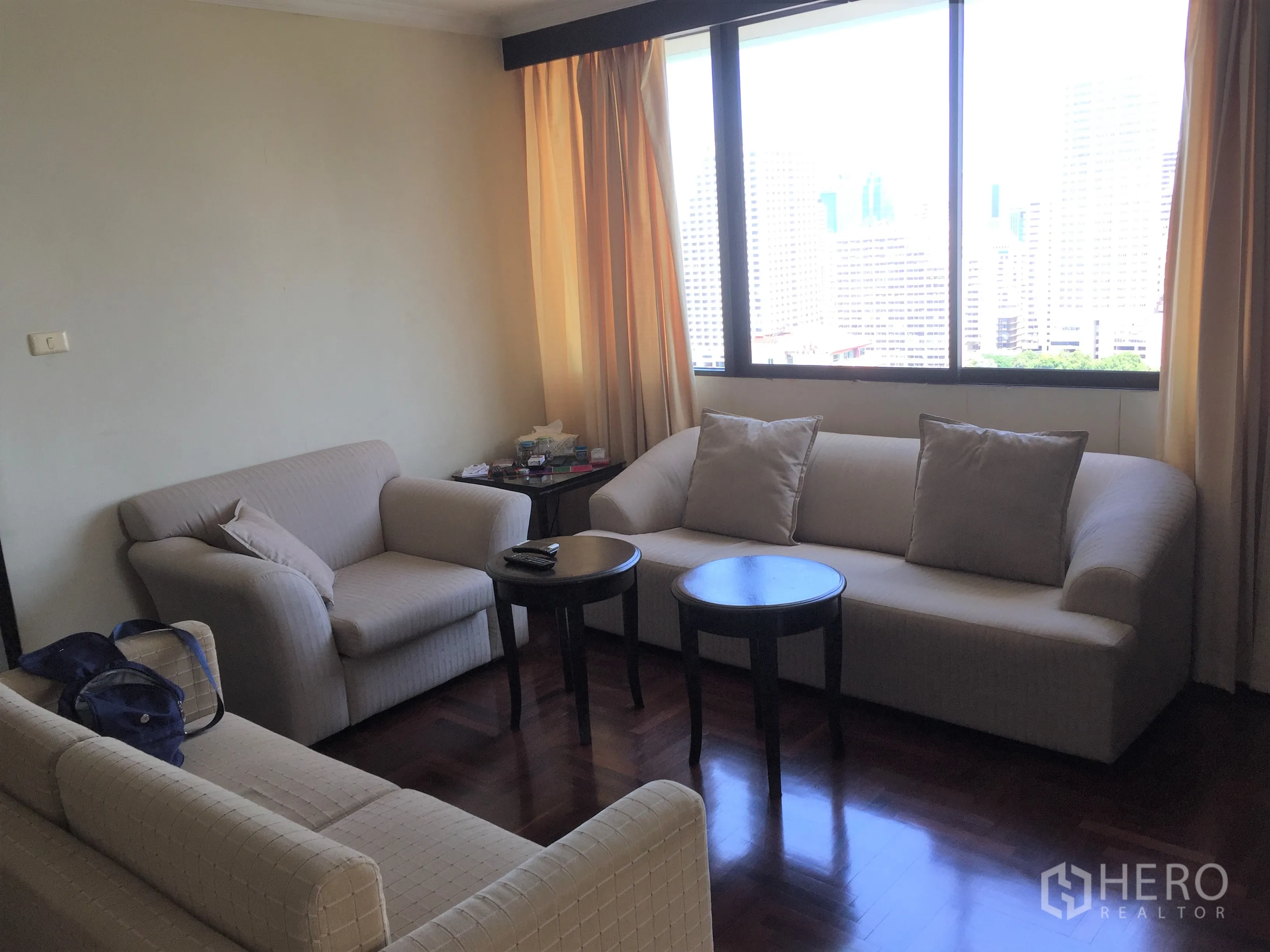 Condominium for rent or sale in Khlong Toei, Bangkok - Cozy sitting corner with three sofas and round coffee tables beside a large window.