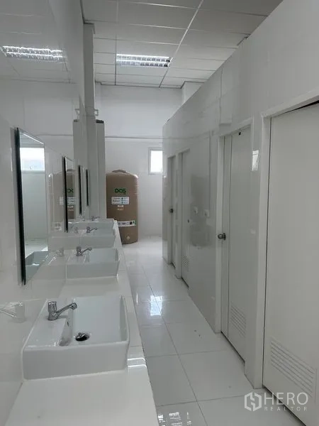 Factory for rent in Khlong Luang, Pathum Thani - Clean staff restrooms with multiple sinks and mirrors in a tiled corridor