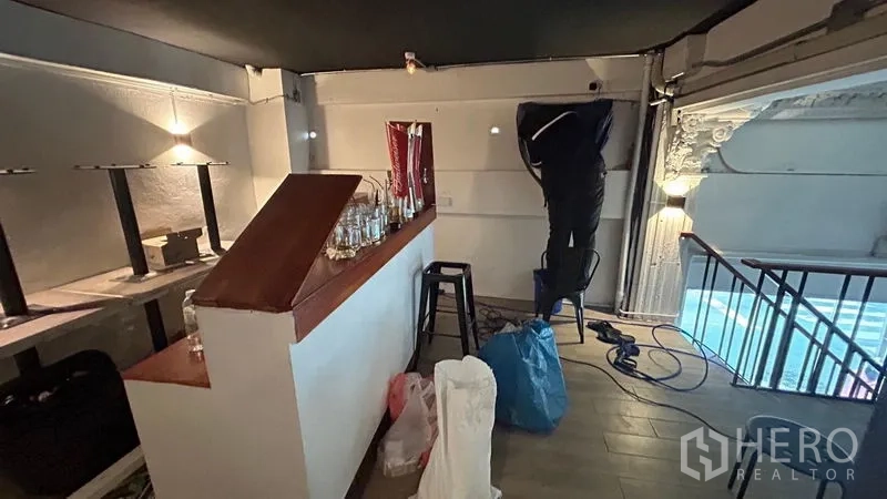 Shophouse for sale - Upper bar area with counter, stools and warm wall lighting.