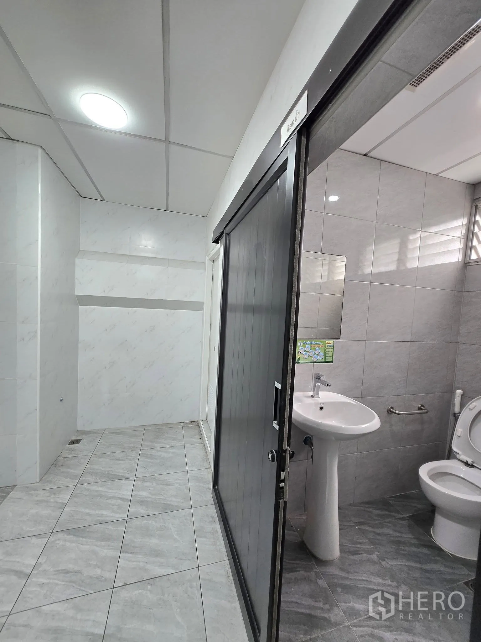 Office Space for rent in Khlong Toei, Bangkok - Hallway with tiled floors leading to an internal bathroom with a pedestal sink and toilet.