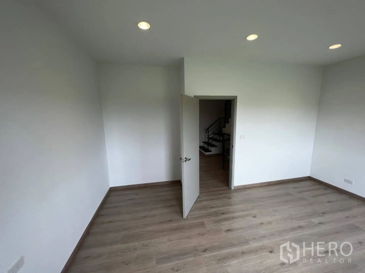 Townhouse for rent in Bang Khen, Bangkok - Bedroom with wood floors and door opening to the stair landing.