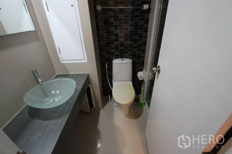 Condominium for rent or sale in Wang Thonglang, Bangkok - Second bathroom featuring a glass vessel sink, toilet, and mosaic-tiled shower zone.