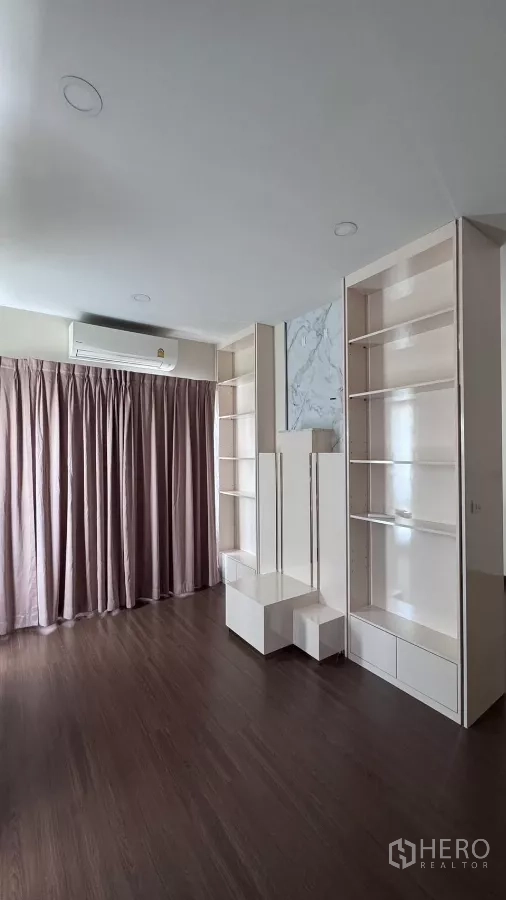 บ้าน ให้เช่าหรือขายในSaphan Sung, Bangkok - ห้องอเนกประสงค์ชั้นบนพร้อมชั้นวางสีขาวบิลท์อิน ผ้าม่านสีชมพู และพื้นไม้สีเข้ม.