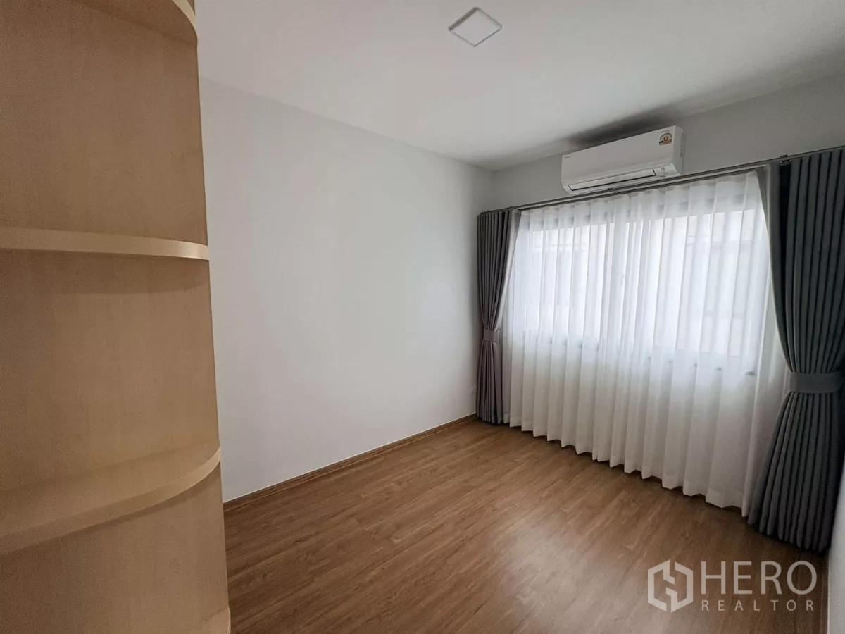 Townhouse for rent in Bang Phli, Samut Prakan - Secondary bedroom with large curtained window, wood floor and air conditioning.
